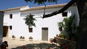A courtyard with white walls, a tiled roof, and potted plants. - Cortijo Molino Los Justos (Algarinejo)