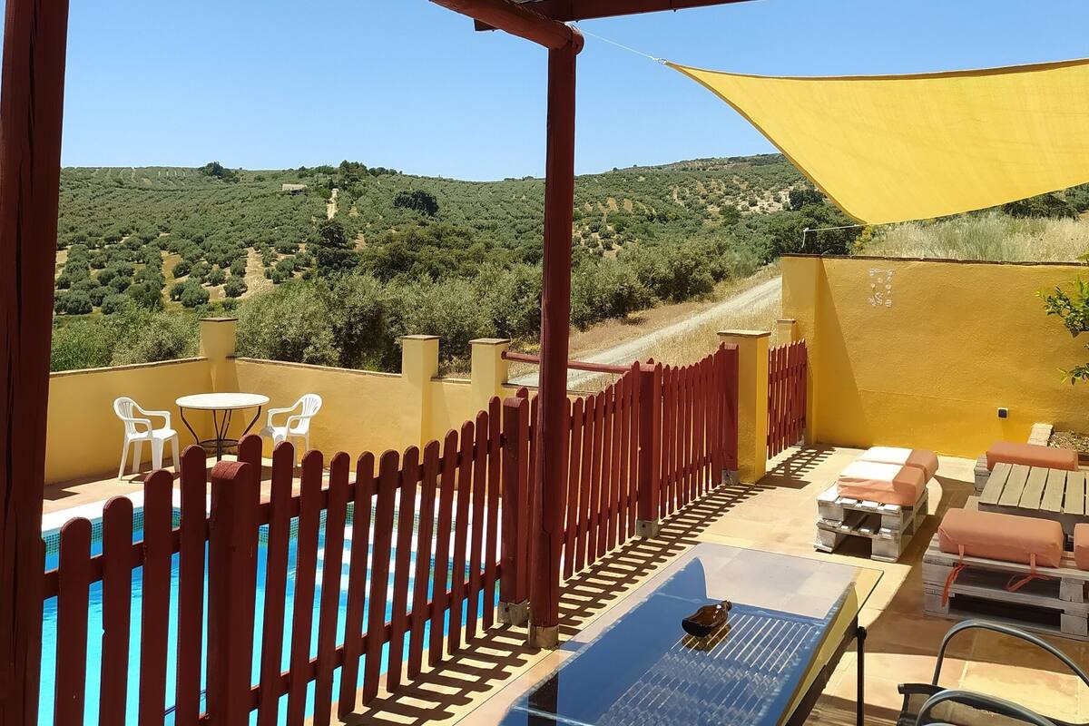 Una terraza con piscina, mobiliario exterior y vistas a un paisaje montañoso.