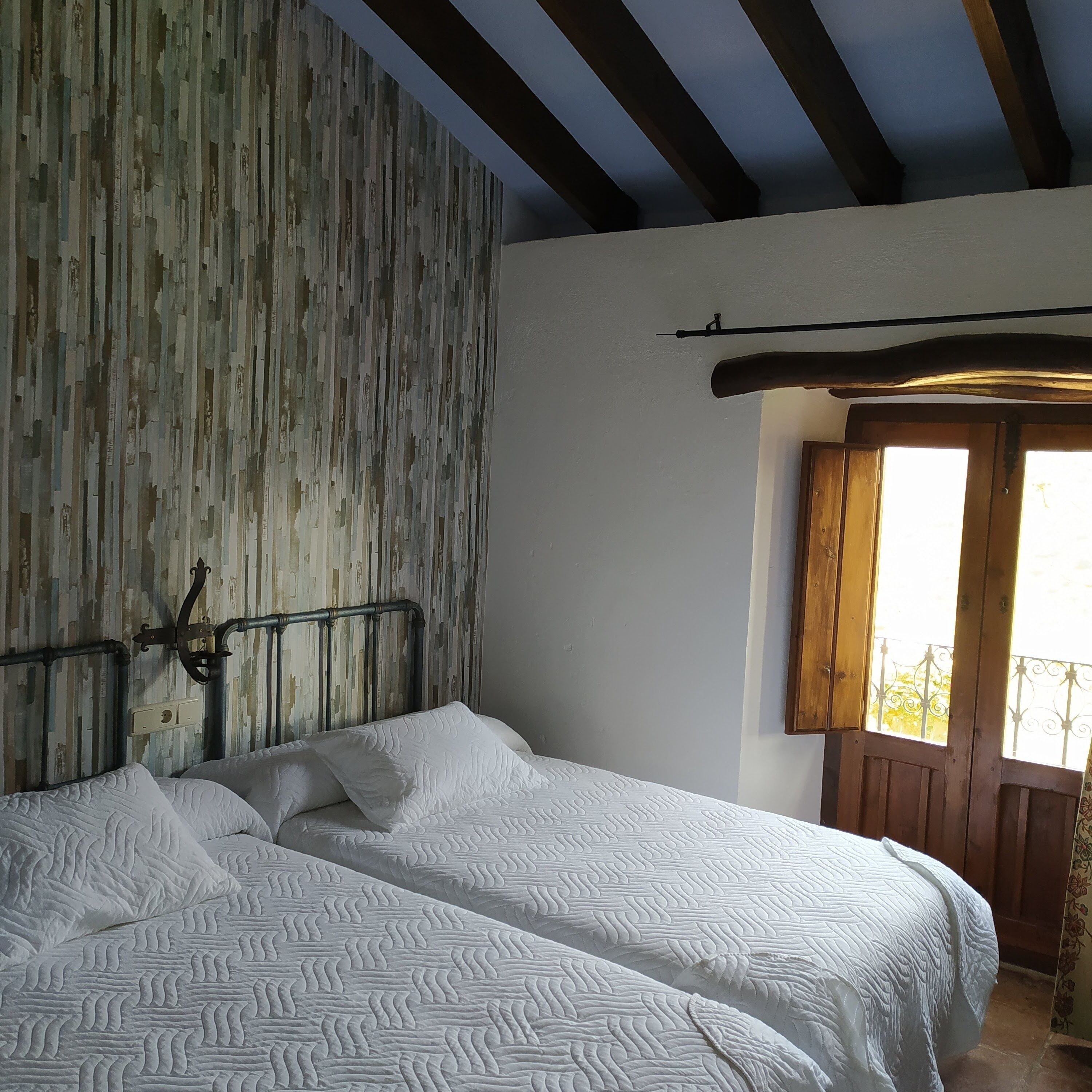 Un dormitorio con dos camas, un panel de pared de listones de madera, techo de madera y una ventana con vistas.
