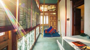 A narrow hallway with a wooden bench, a hanging light fixture, and a door with a glass panel. - Mangaldas Ni Haveli II by The House of MG (Ahmedabad)