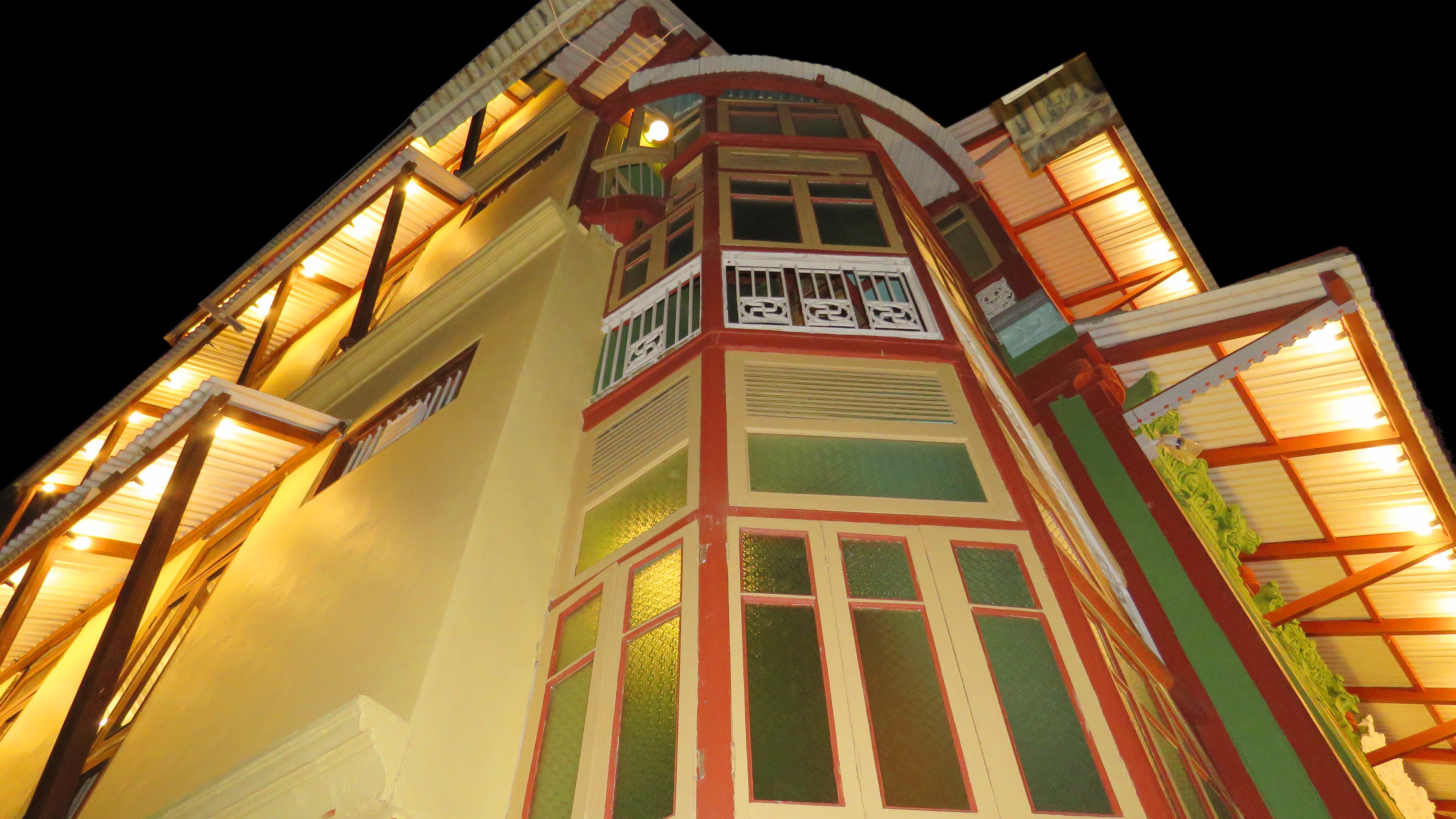 Un edificio de varios pisos con un estilo arquitectónico distintivo, que presenta un balcón con barandillas ornamentadas y una serie de ventanas con marcos decorativos.