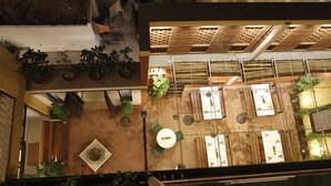 An indoor courtyard with potted plants, a central fountain, and multiple seating areas. - Mangaldas Ni Haveli II by The House of MG (Ahmedabad)