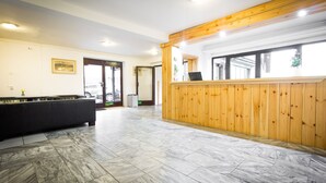 Un vestíbulo amplio con mesa de billar, mostrador de recepción de madera y un ventanal con vistas al exterior.