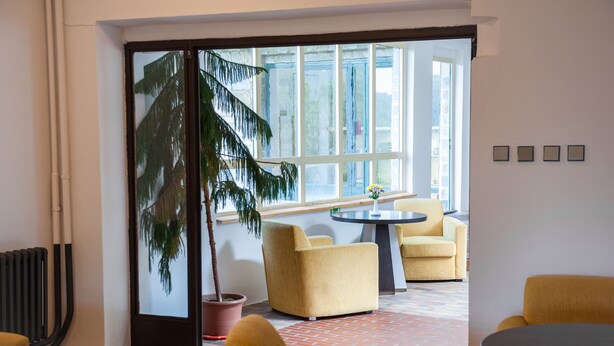 Un interior moderno con sillones amarillos, una mesa redonda y un amplio ventanal con vistas.