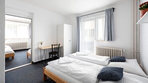 Una habitación de hotel moderna con dos camas individuales, un escritorio, una silla y un radiador.