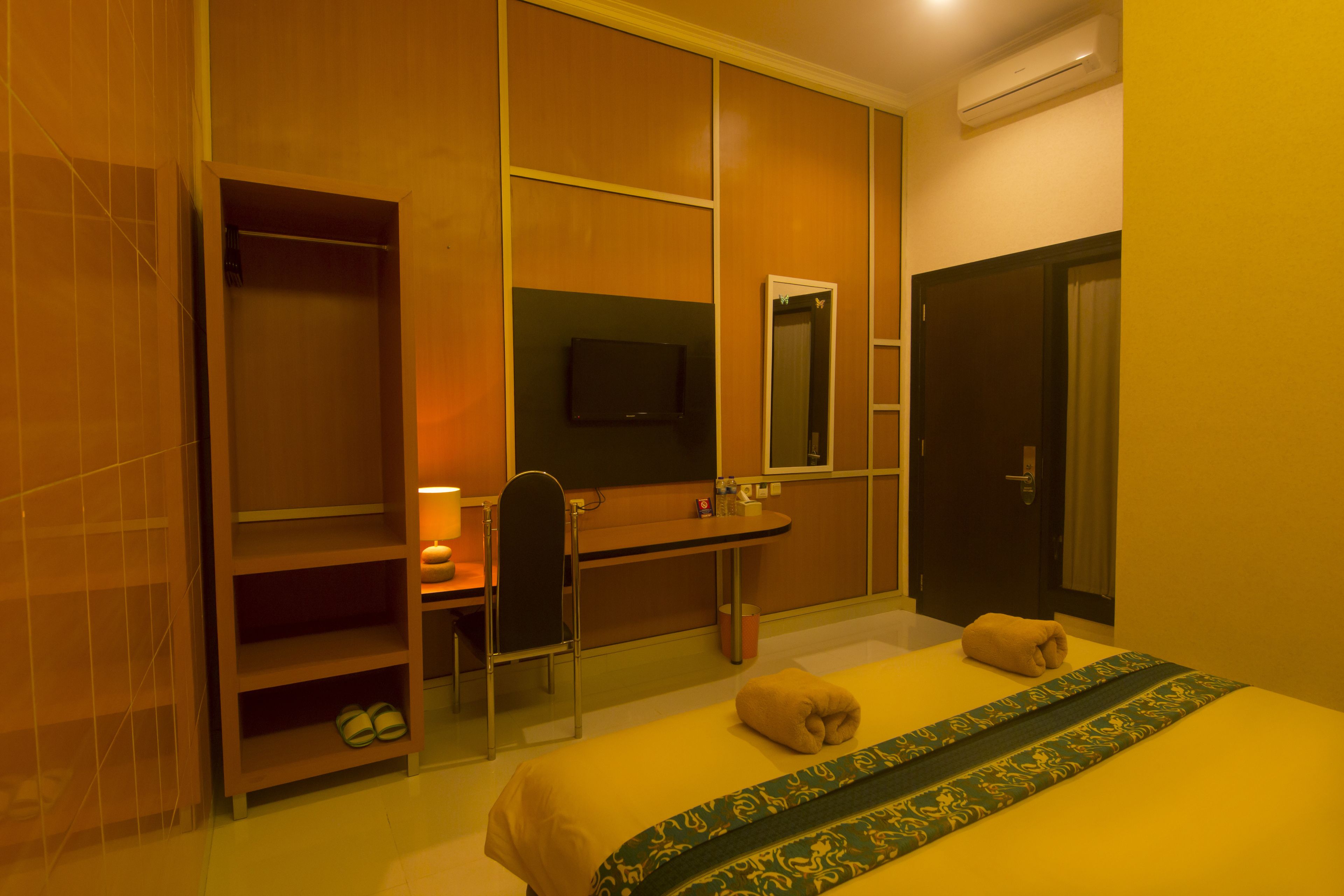 A hotel room with a bed, a desk, a chair, a TV, and a wardrobe.
