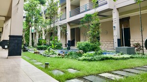 A courtyard with a swimming pool, surrounded by greenery and a multi-level building with balconies. - Savita Garden Inn (Ngaglik)