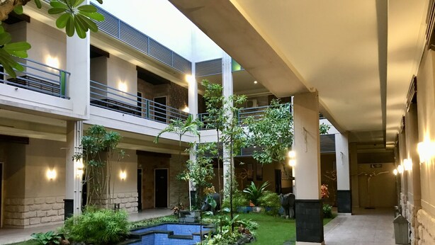 A multi-level indoor courtyard with a swimming pool, greenery, and a stone pathway. - Savita Garden Inn (Ngaglik)