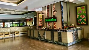 A hotel reception area with a marble counter, a sign reading "Savitahm," and a floral wall decoration. - Savita Garden Inn (Ngaglik)