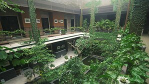 A multi-level indoor garden with various plants, seating areas, and a small water feature. - Savita Garden Inn (Ngaglik)