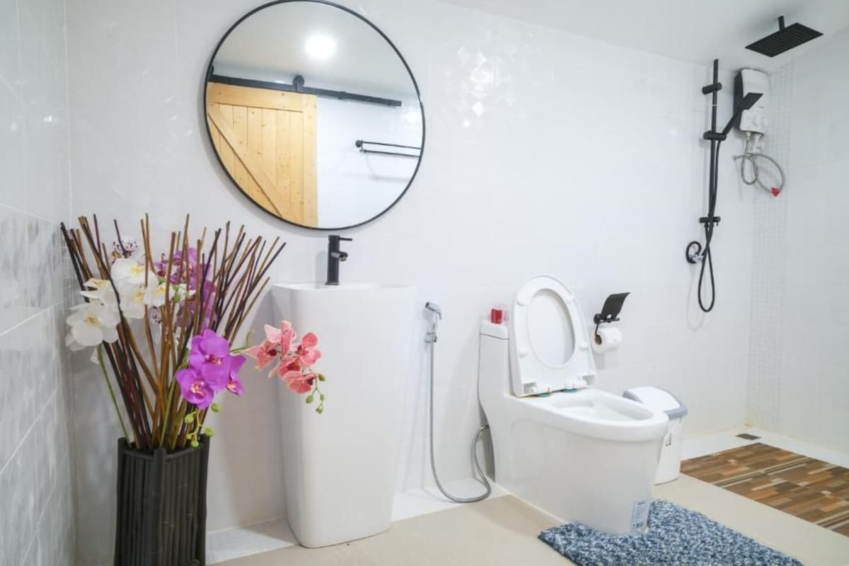 Une salle de bain équipée de toilettes, d’un bidet, d’une douche et d’un miroir.