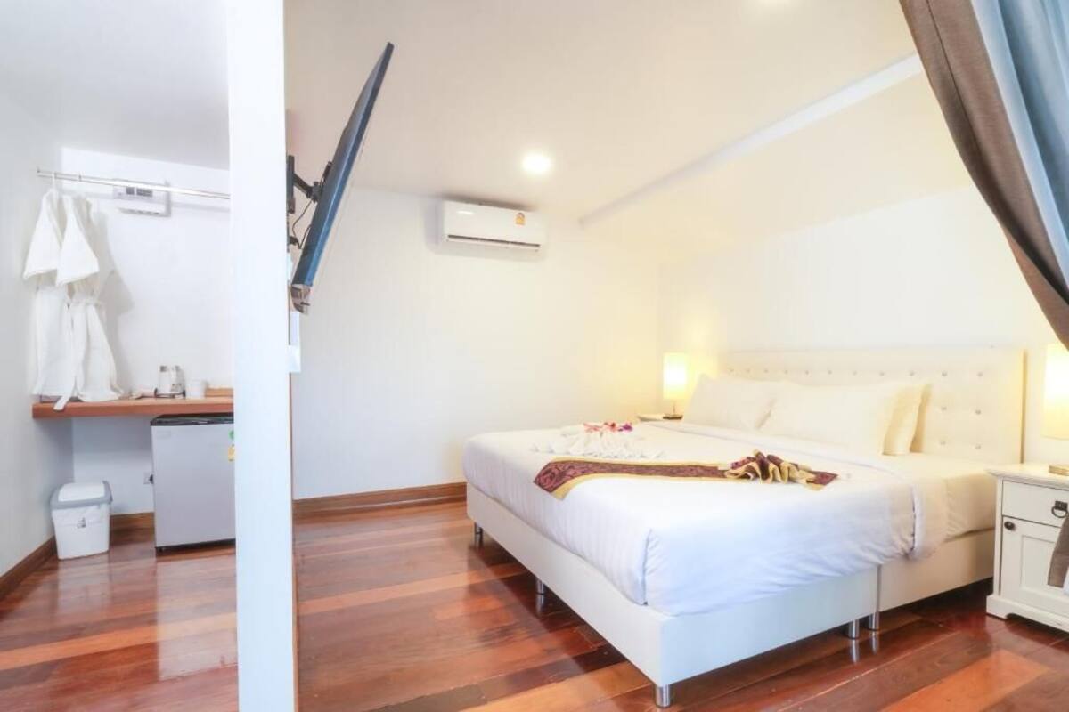 Une chambre à coucher comprenant un lit, une table de chevet, une lampe, un appareil de climatisation et un petit bureau avec une chaise.