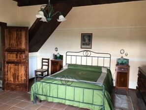 Ein Schlafzimmer mit einem Bett, einem Holzschrank und einem Schreibtisch mit Stuhl.