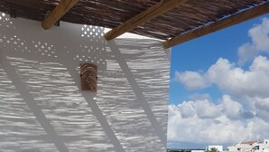 An outdoor seating area with a white table and chairs, a cushioned sofa, and a pergola overhead. - My Rooms Ciutadella - Adults Only by My Rooms Hotels (Ciutadella de Menorca)