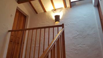 A wooden staircase with a handrail, a door, and a wall-mounted light fixture.