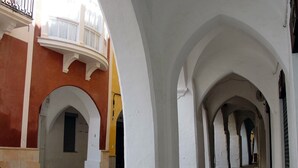A corridor with white arches and a yellow building on one side. - My Rooms Ciutadella - Adults Only by My Rooms Hotels (Ciutadella de Menorca)