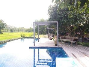 En swimmingpool med træterrasse og pergola.