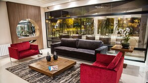 A modern living room with a red sofa, a black sofa, and a wooden coffee table. - Gaboardi Park Hotel (Curitibanos)