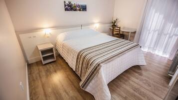 A neatly arranged bedroom with a bed, bedside tables, a small table, and a wall-mounted picture.