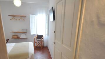 Un pasillo estrecho con una cama, una silla y una puerta con el número 6.