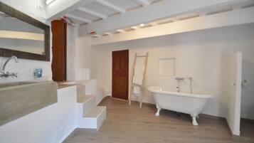 Ein Badezimmer mit einer freistehenden Badewanne, einer Holzleiter und einem großen Spiegel.