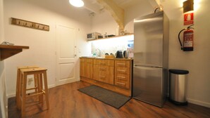 A compact kitchen with wooden cabinets, a stainless steel refrigerator, a microwave, and a small stool. - Port Antic Ciutadella  by My Rooms Hotels (Ciutadella de Menorca)