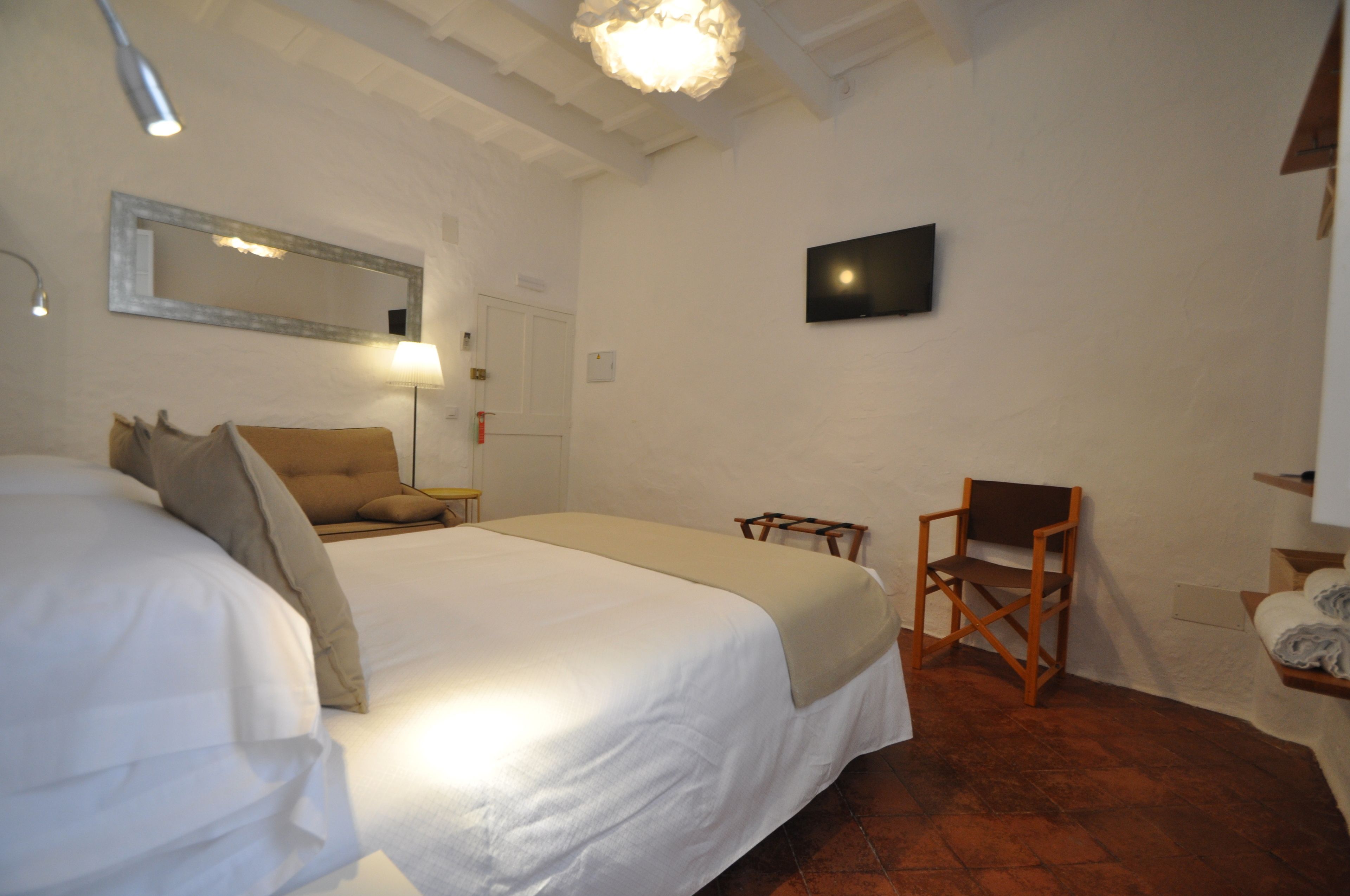 Una habitación de hotel con una cama grande, una silla, un escritorio, un televisor y un espejo en la pared.