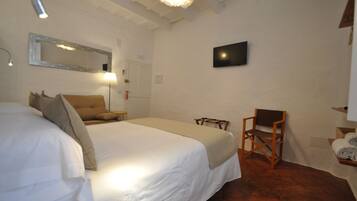 Una habitación de hotel con una cama grande, una silla, un escritorio, un televisor y un espejo en la pared.
