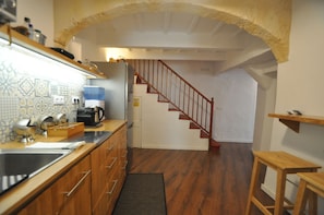 Eine Küche mit Holzschränken, einem Spülbecken und einer Treppe zu einer weiteren Ebene.