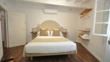 A neatly arranged bedroom with a bed, bedside tables, a hanging light fixture, and a built-in shelf with towels.