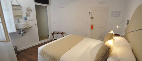 A bedroom with a bed, bedside lamp, and a small bedside table.