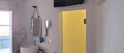 A bathroom with a white sink, mirror, and a yellow door.