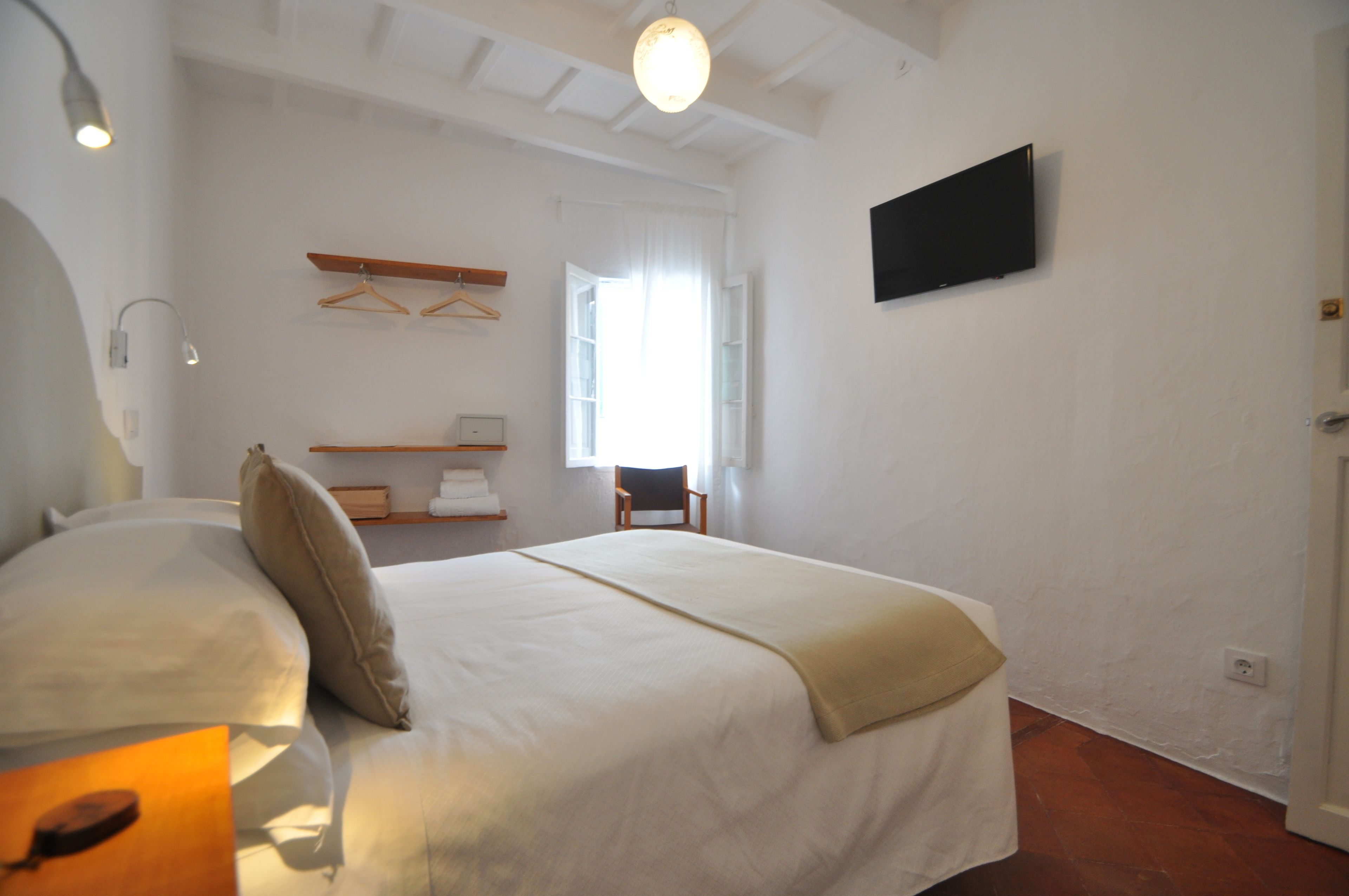 Een slaapkamer met een bed, een stoel, een televisie en een raam.