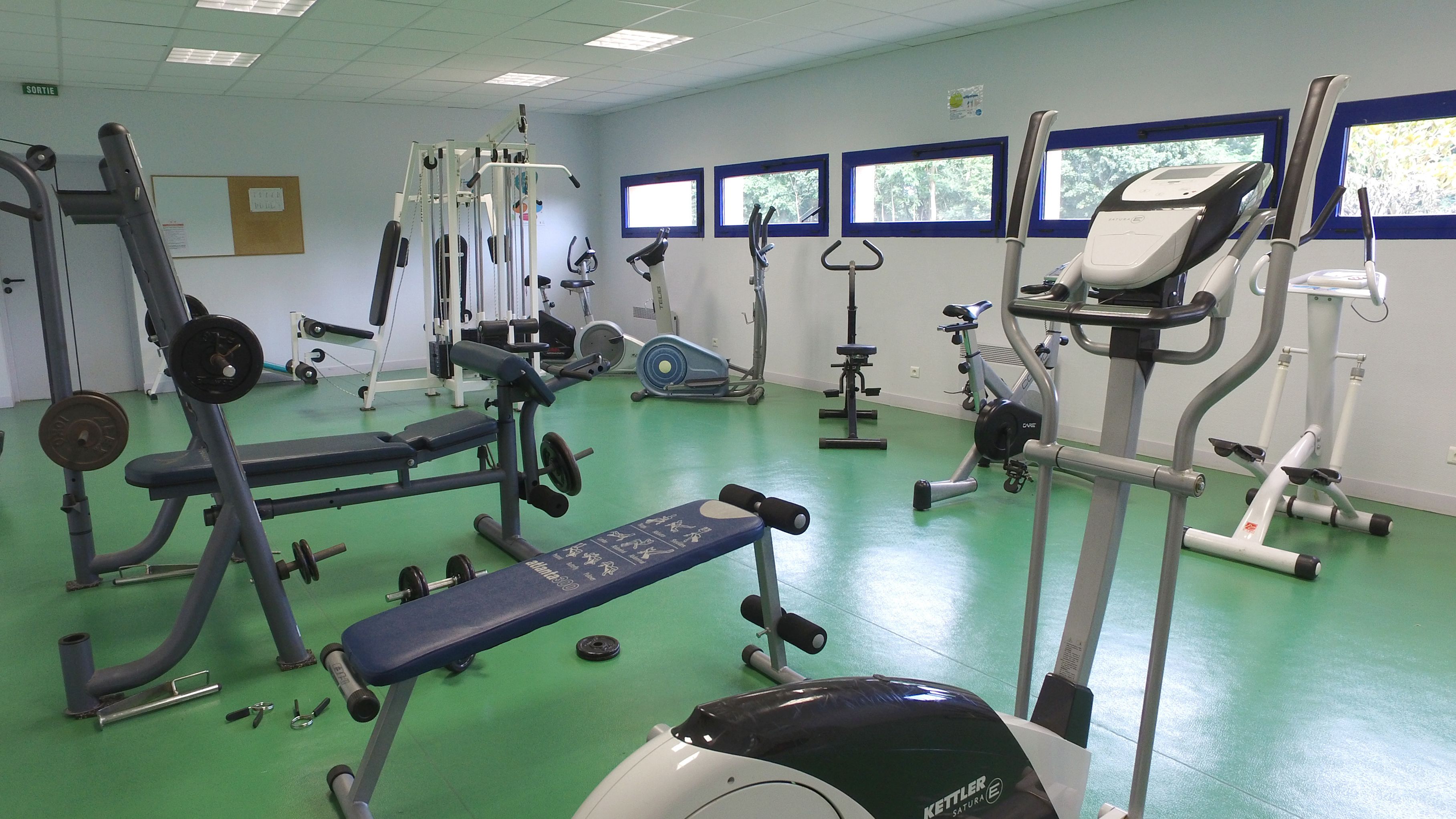 A gym with various exercise equipment, including a bench press, weight machines, and cardio machines.