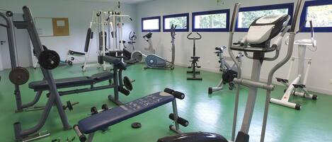 A gym with various exercise equipment, including a bench press, weight machines, and cardio machines.