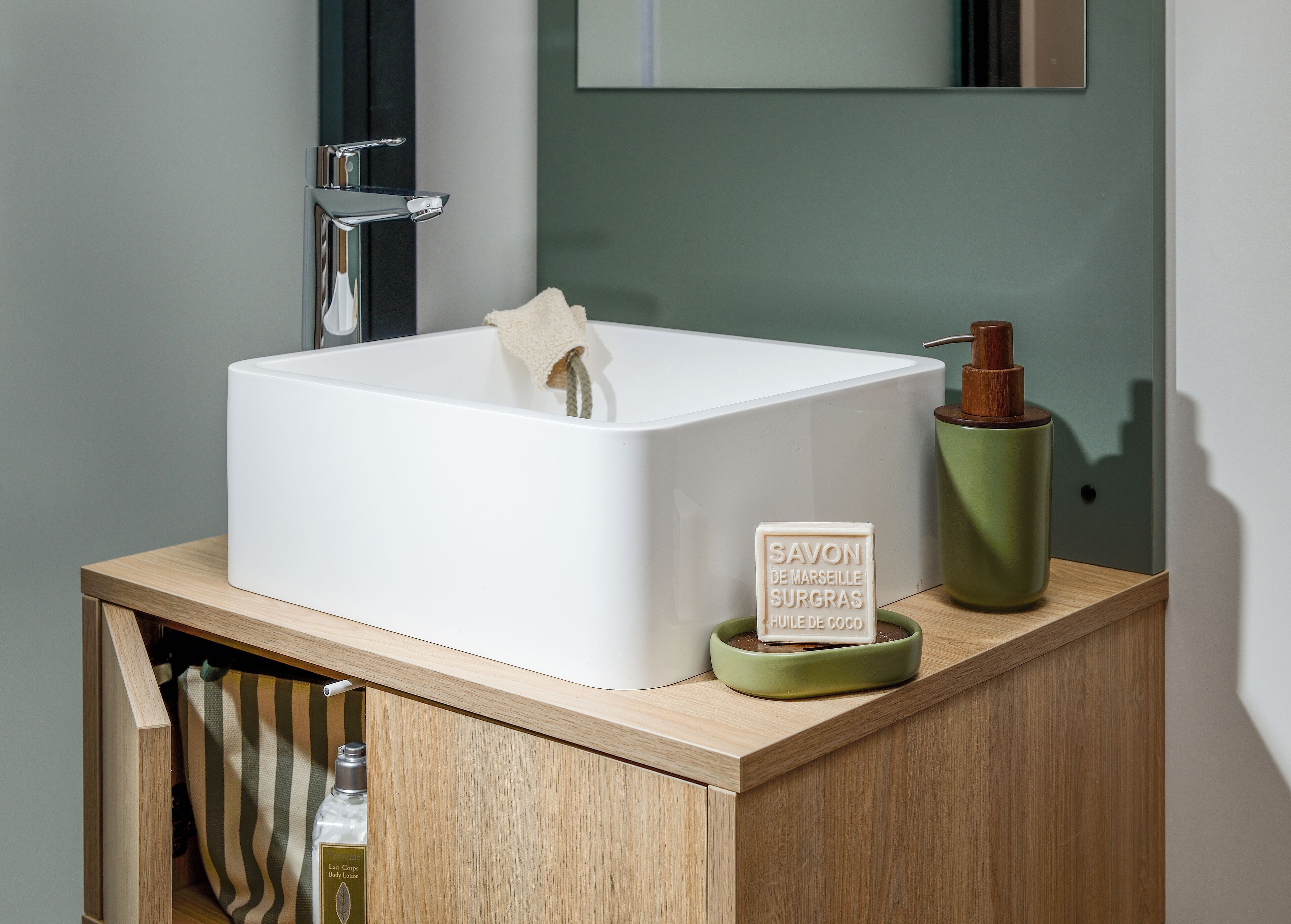A bathroom with a white sink, a green soap dispenser, and a bottle of shampoo.