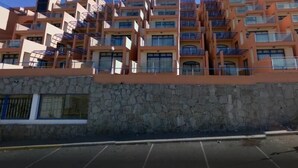 A multi-story hotel with balconies and a stone facade. - Balcon de Taurito (Mogan)