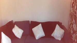 A dark-colored sofa with three white cushions. - Balcon de Taurito (Mogan)