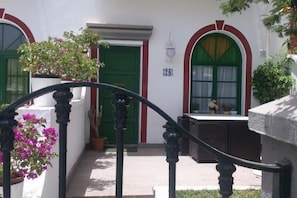 A building with a green door, a number '28' on the wall, and a window with a curtain. - Balcon de Taurito (Mogan)