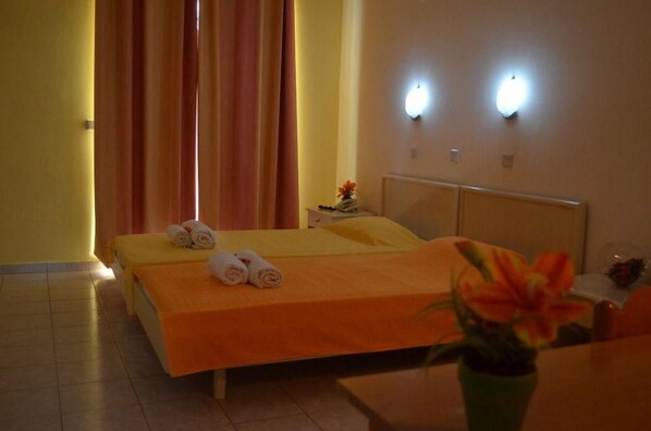 A hotel room with a bed, a nightstand, a vase with flowers, and two wall-mounted lights.