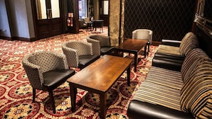 A lobby with patterned carpet, a wooden coffee table, patterned chairs, and a striped sofa. - Dillons Hotel (Letterkenny)