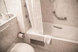 A bathroom with a bathtub, toilet, and a shower curtain. - Dillons Hotel (Letterkenny)