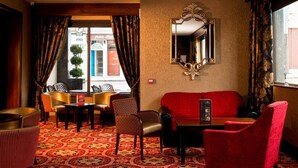 A hotel lobby with a red sofa, patterned carpet, and a large mirror on the wall. - Dillons Hotel (Letterkenny)