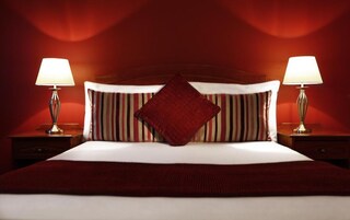Una habitación de hotel con una cama grande, almohadas a rayas y dos lámparas de noche.