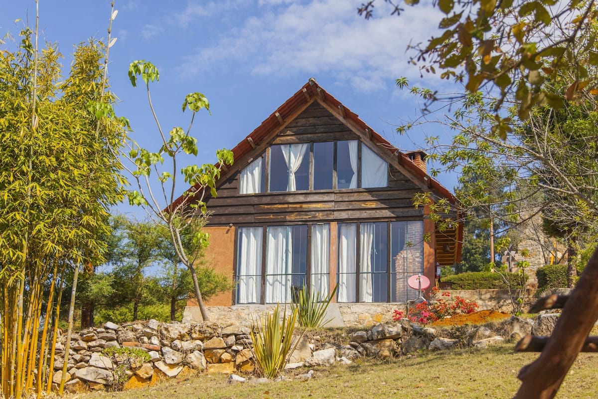 A rustic house with a stone foundation, wooden exterior, and large windows.