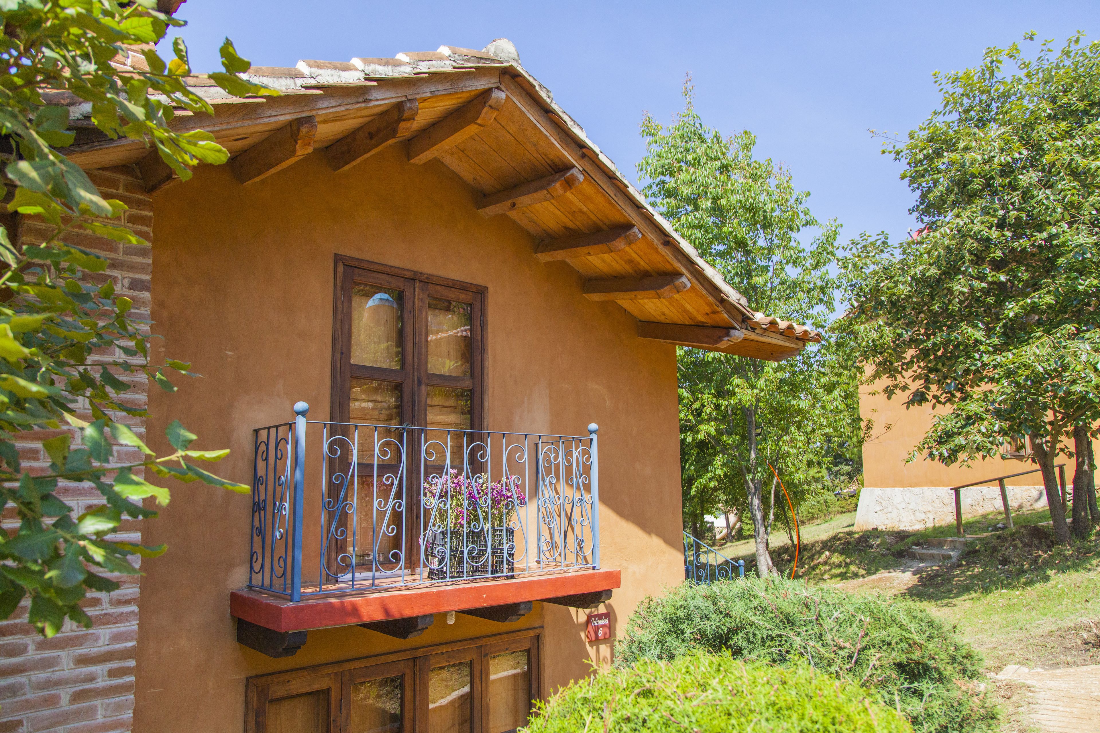 A rustic building with a wooden balcony, a window, and a brick wall.
