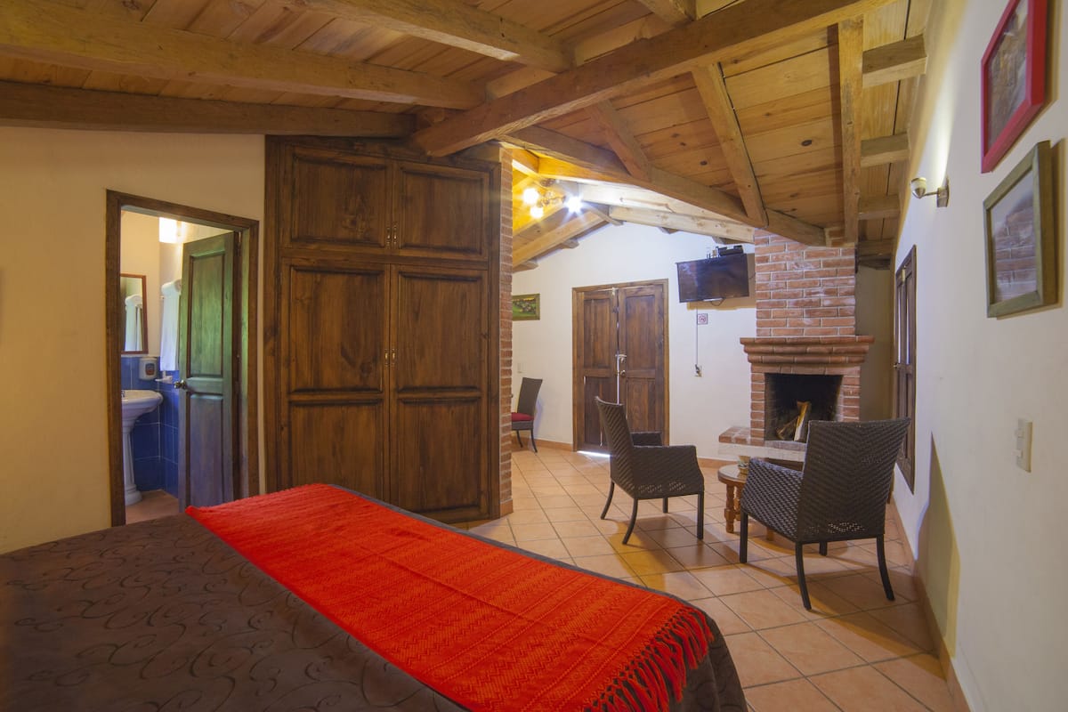 A room with a bed, a fireplace, and a dining area.