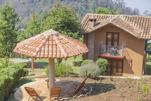 A house with a tiled roof, a balcony with metal railings, and a patio area with a tiled umbrella and wooden chairs. - Cabañas y Suites Sergia Torres (San Cristóbal de las Casas)