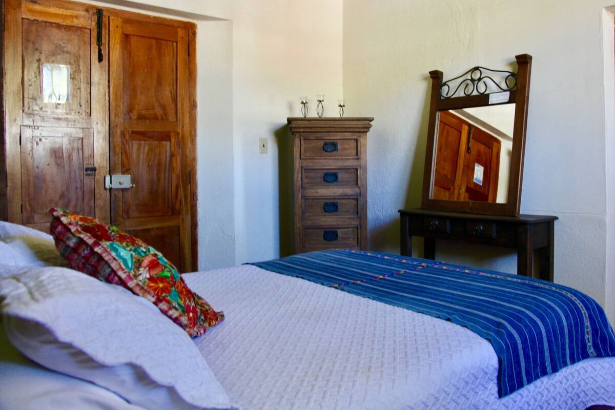 Une chambre à coucher avec un lit, une commode, un miroir et des portes en bois.
