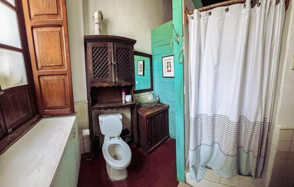 A bathroom with a wooden cabinet, a toilet, a sink, and a shower curtain.